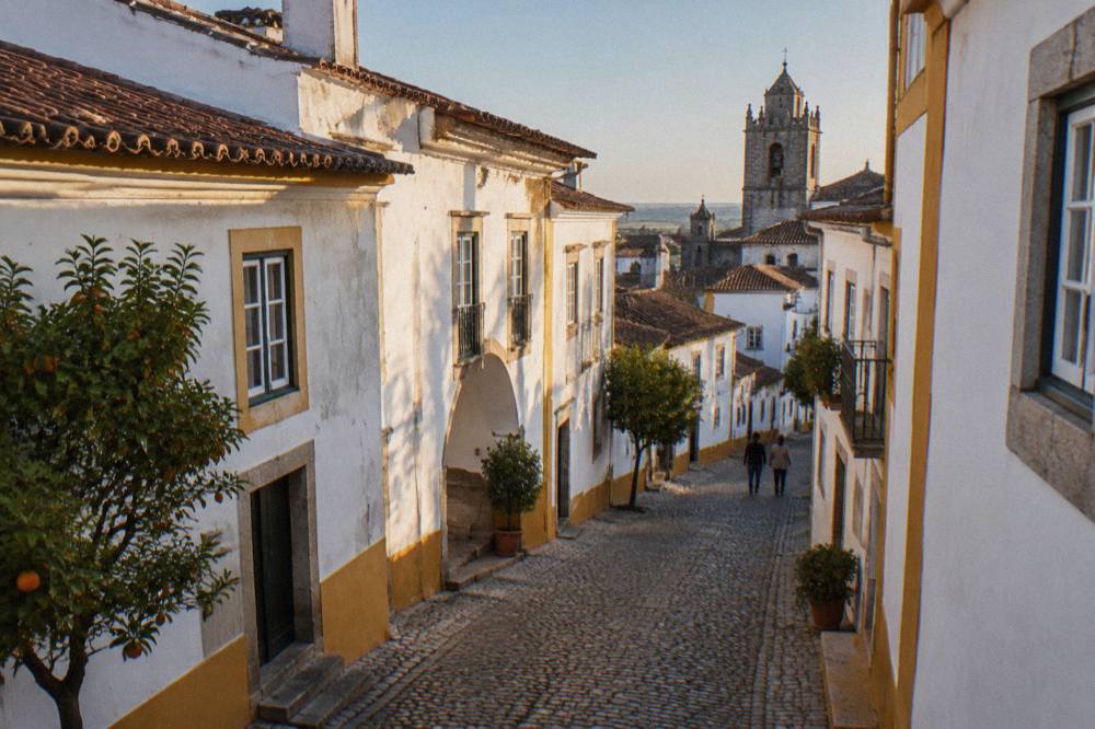 Golden late-afternoon light on a narrow whitewashed street in Évora's historic centre