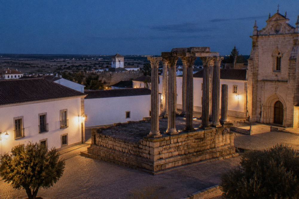 The Roman temple of Évora standing in the open air at dusk, with columns silhouetted against the sky