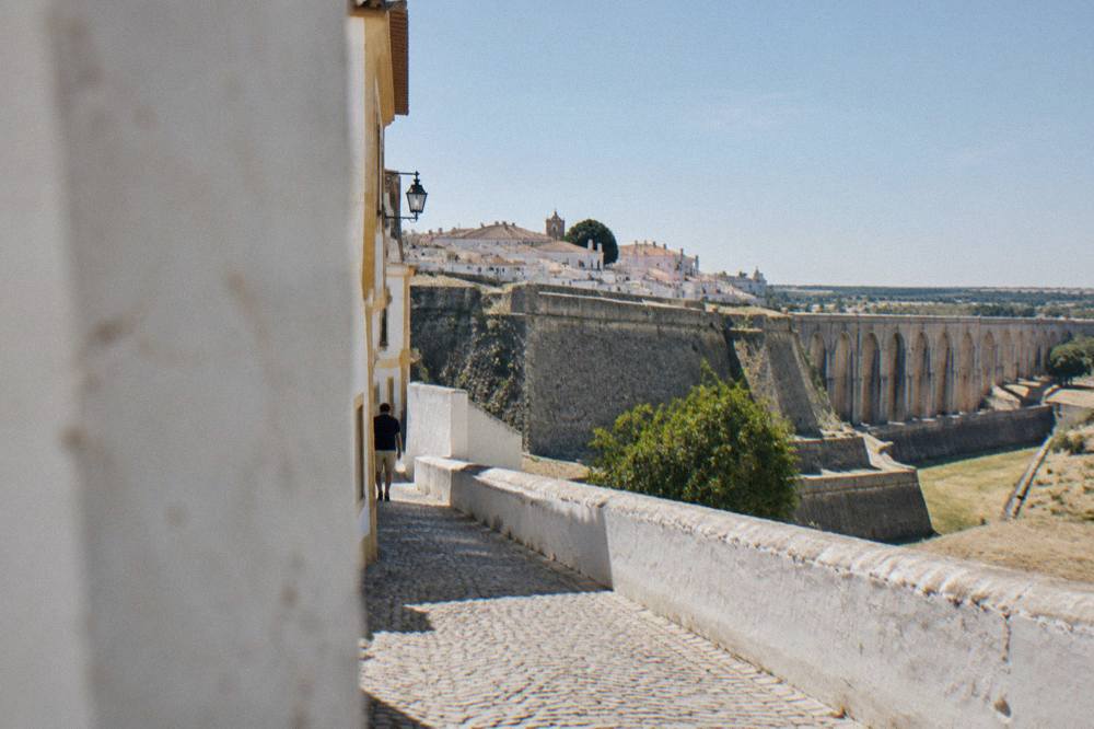 A quiet cobbled street of white-walled houses in a fortified Alentejo town at midday
