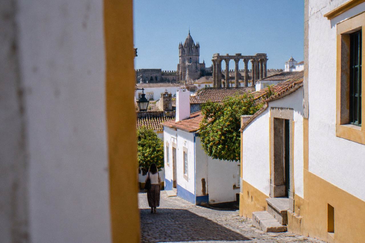 Évora's walled old town seen from a rooftop, with the Roman temple columns and the cathedral tower rising above whitewashed houses