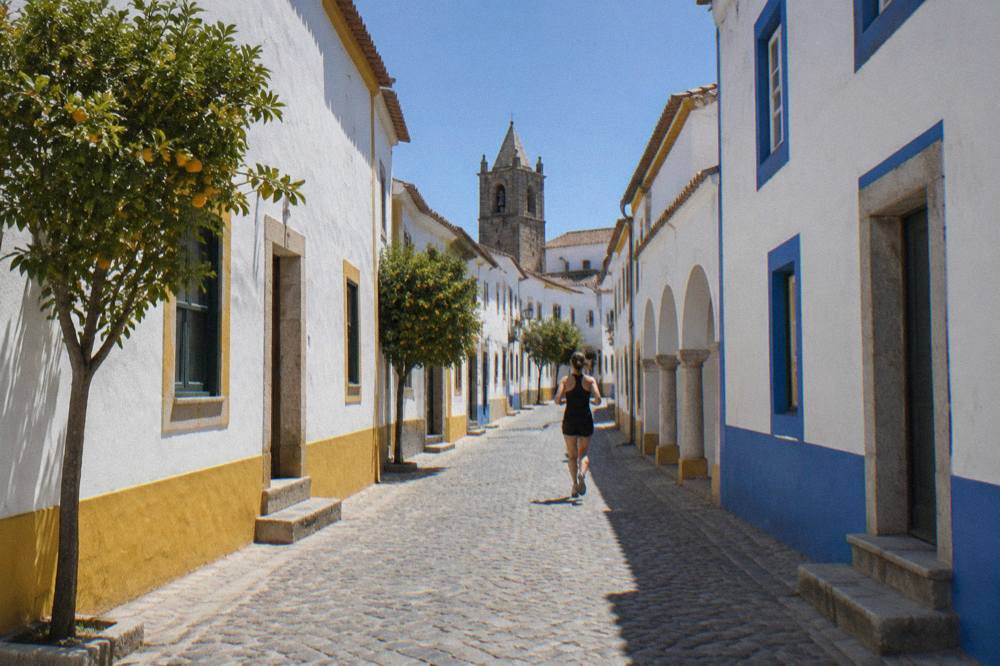 A whitewashed street with blue and yellow trim in the historic centre of Évora under a clear sky