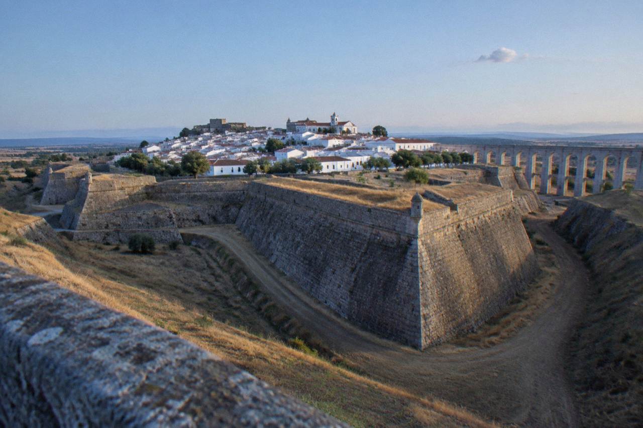 Star-shaped stone bastion walls of a hilltop fortress town on a dry Alentejo plain under a wide sky