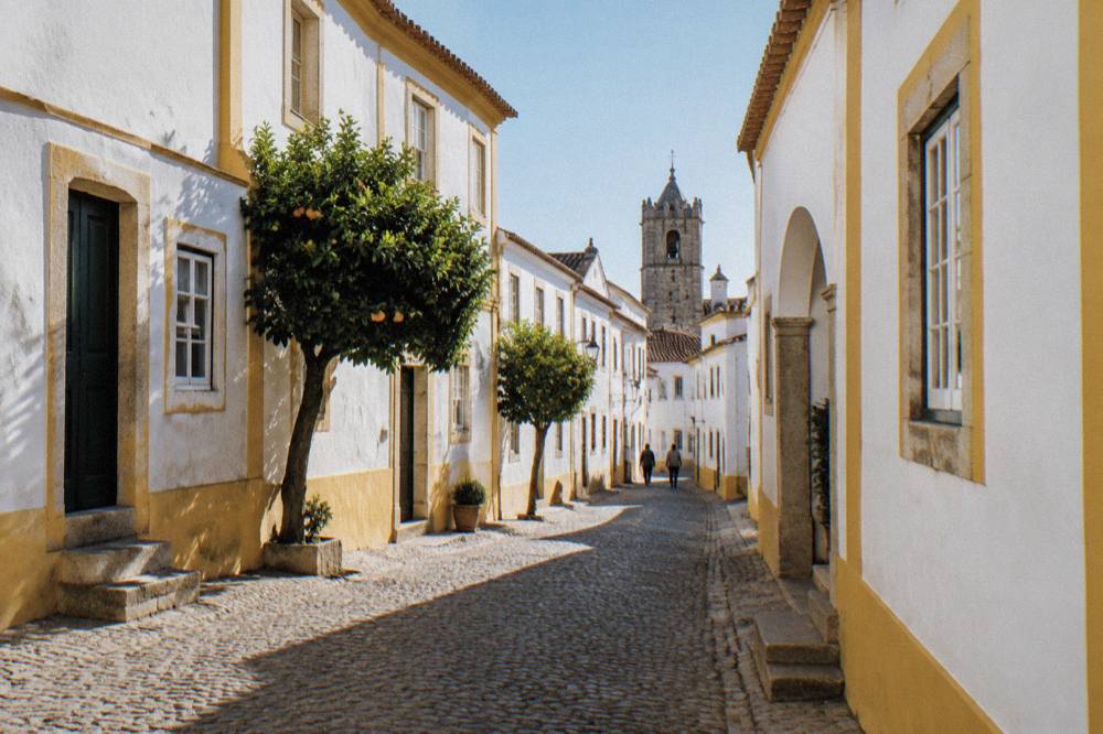 Whitewashed houses with yellow trim along a narrow street in the historic centre of Évora