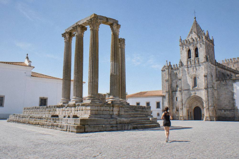The columns of the Roman temple in Évora seen against a clear blue sky beside the cathedral