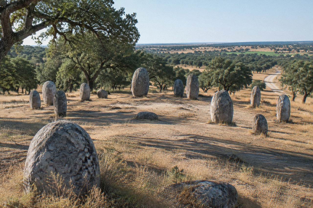 Standing stones of the Almendres cromlech rising from open Alentejo countryside near Évora