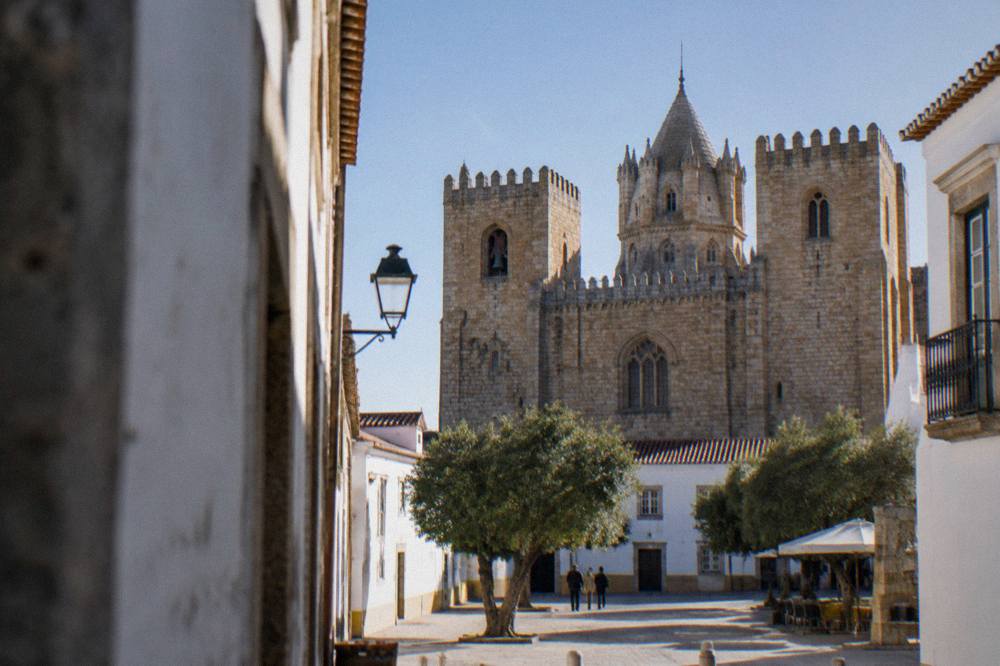 The golden stone towers of Évora cathedral seen from a narrow street in the late afternoon