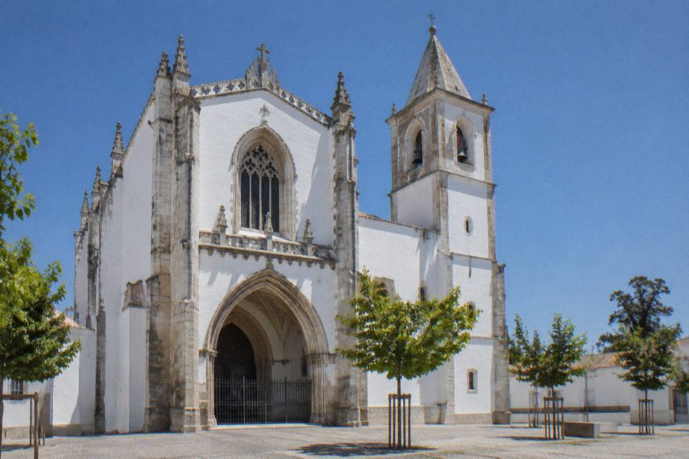 Exterior view of the Igreja de São Francisco in Évora with its large Gothic facade and a bell tower under a clear sky