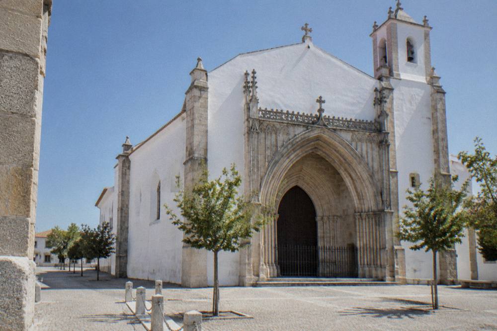 Exterior of the Igreja de São Francisco in Évora with its Gothic portal and plain white walls under a blue sky