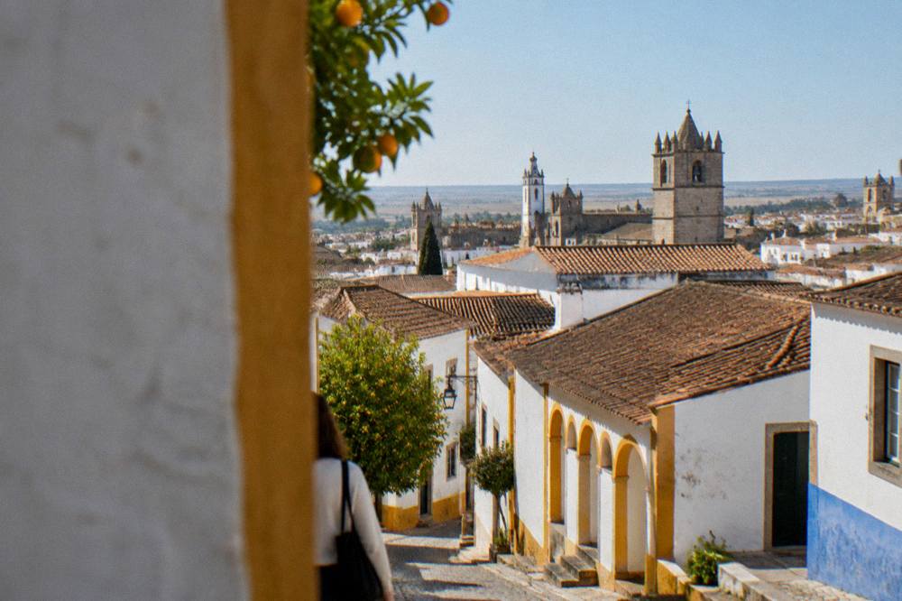 A wide view over the rooftops and church towers of the historic centre of Évora at golden hour