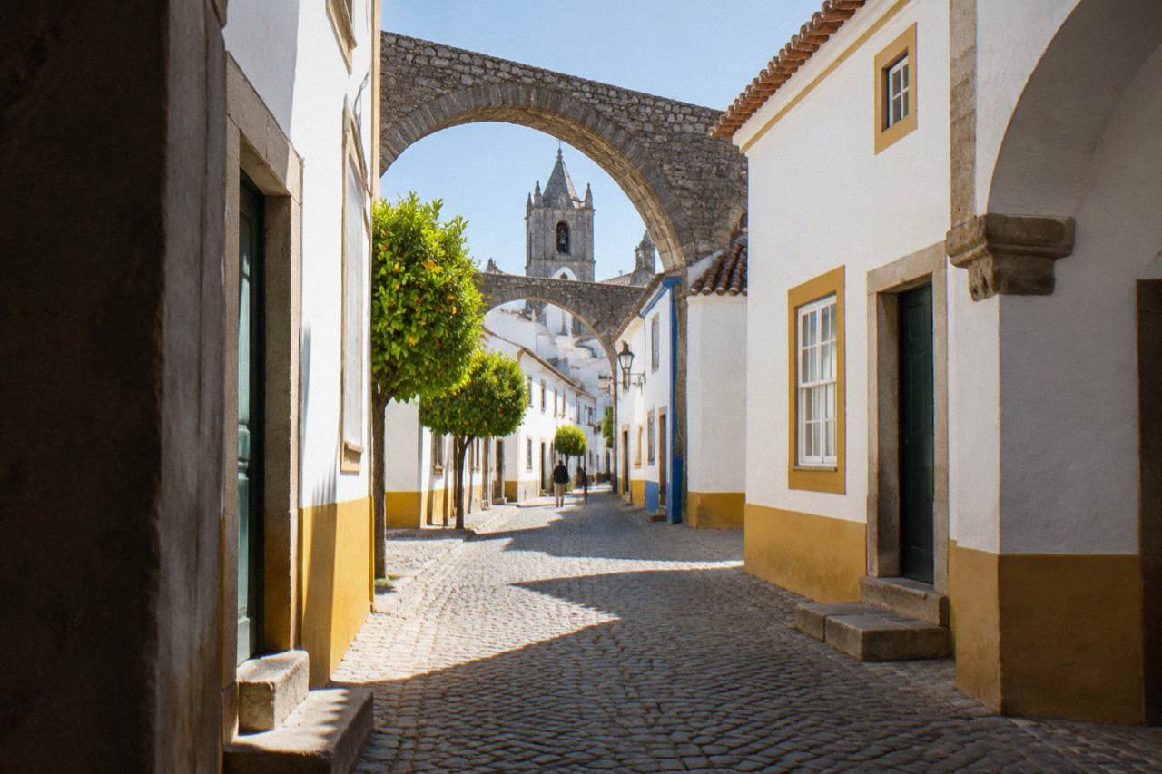 Stone arches of an old aqueduct curving between white houses in Évora