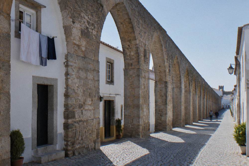 A pedestrian lane running beneath arches with laundry hanging from a window above