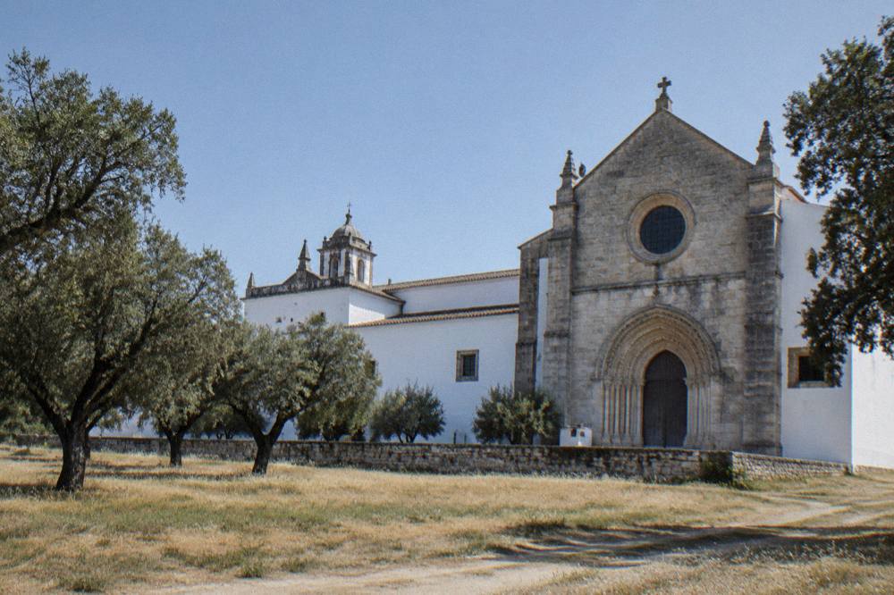 A church portal carved in stone with a round window above it, part of the Cartuxa Monastery complex