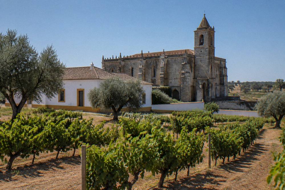 Stone facade of a historic Portuguese monastery with a bell tower under a blue sky