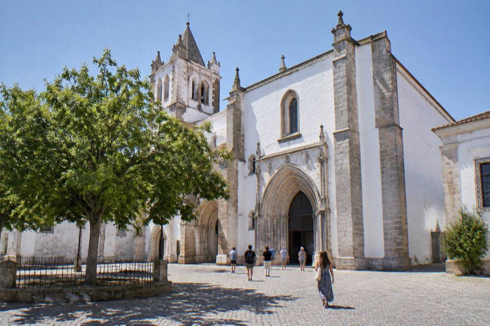 Visitors walking toward the entrance of the Igreja de São Francisco complex in Évora on a bright afternoon