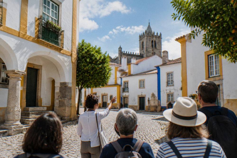 A guide leading a small group of visitors through a cobbled square in the historic centre of Évora