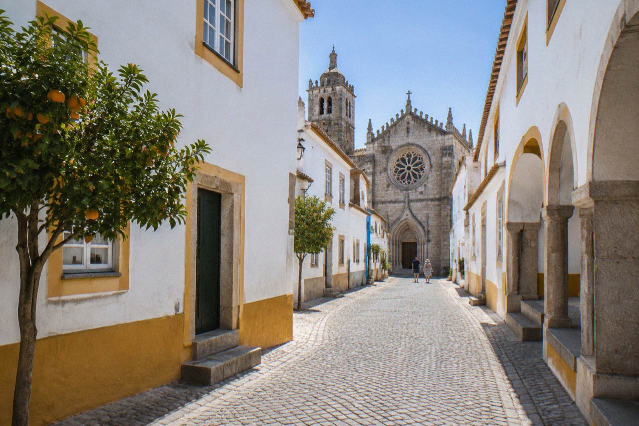 Gothic church facade with a large rose window and arched doorway under a blue sky in Évora