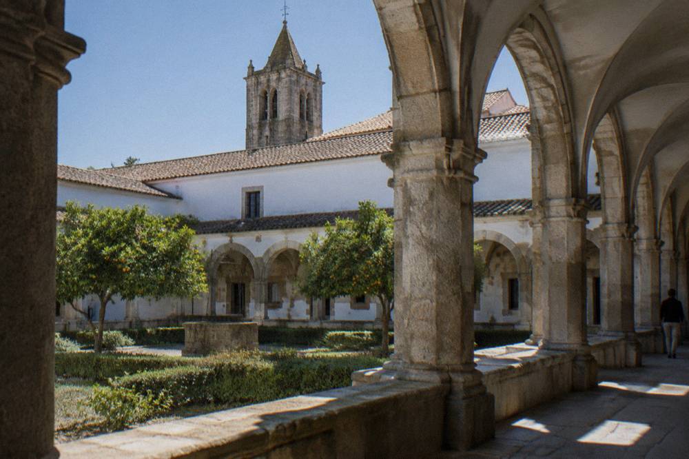 The cloister of an old convent in Évora with stone arches and afternoon light