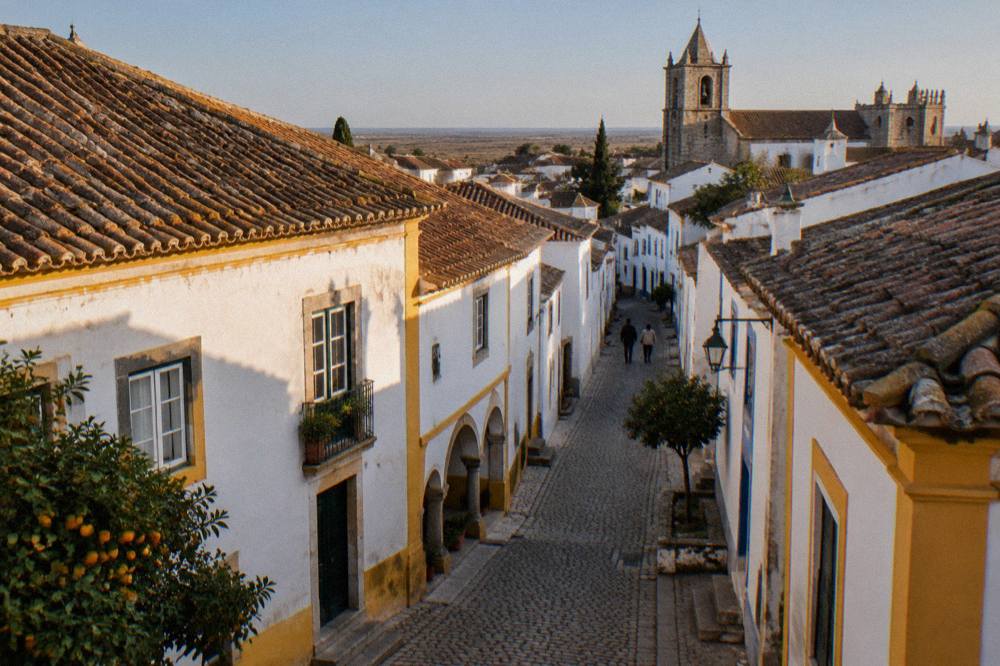 Golden evening light on the tiled rooftops and church towers of Évora seen from above