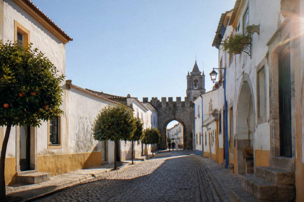 Old stone city wall and arched gate in Évora under a clear sky