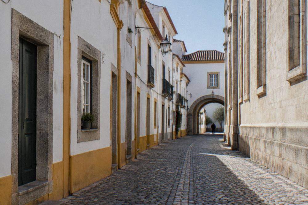 Narrow whitewashed lane in Évora's medieval centre with yellow trim