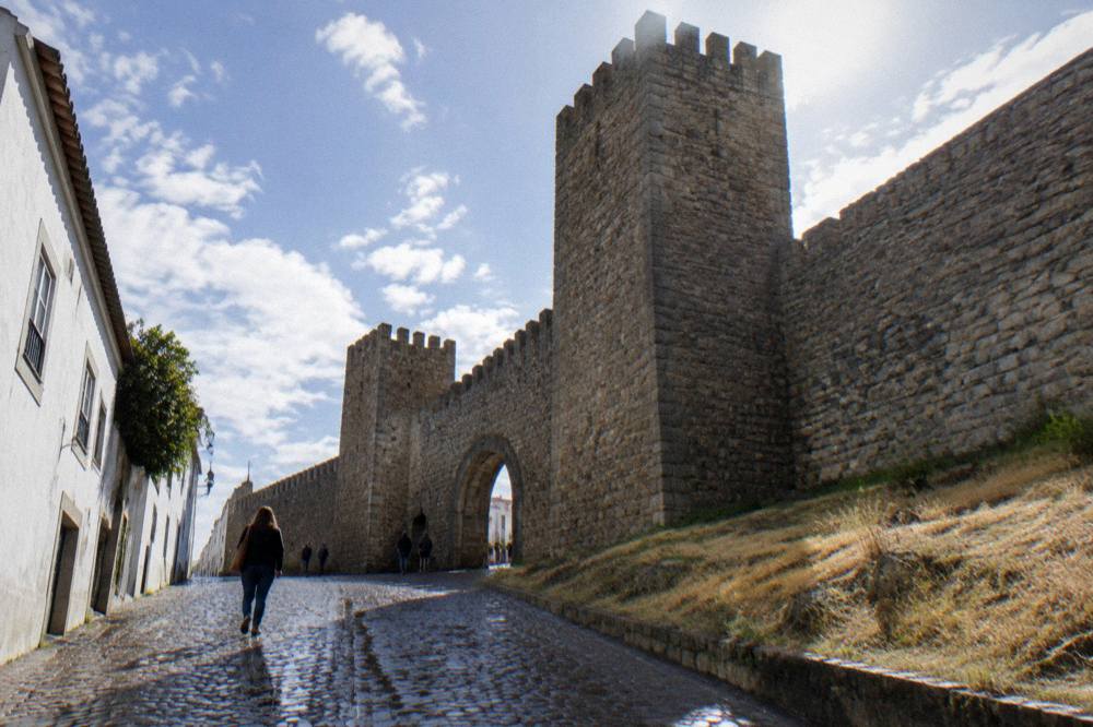 Visitor walking a cobbled street inside Évora's city walls