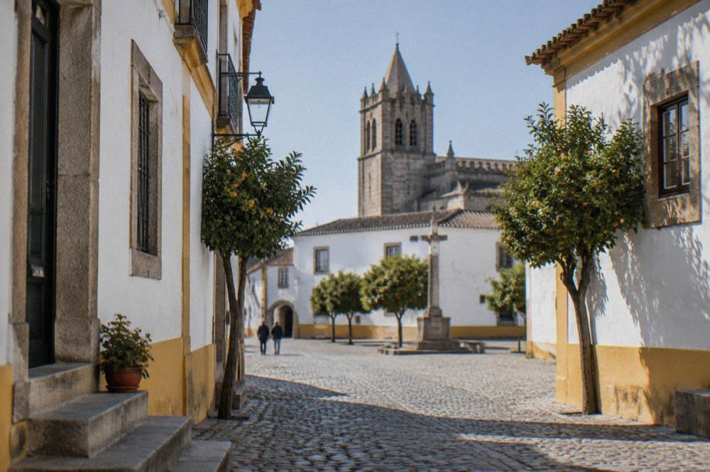 Cobbled square in a Portuguese historic centre with a cathedral tower in the background