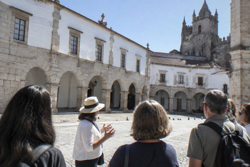 Guide speaking to a small group beside old stone buildings in a Portuguese square