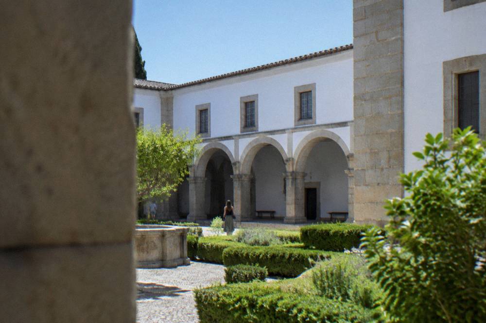 Stone facade of a former palace housing the Museu de Évora beside a green garden
