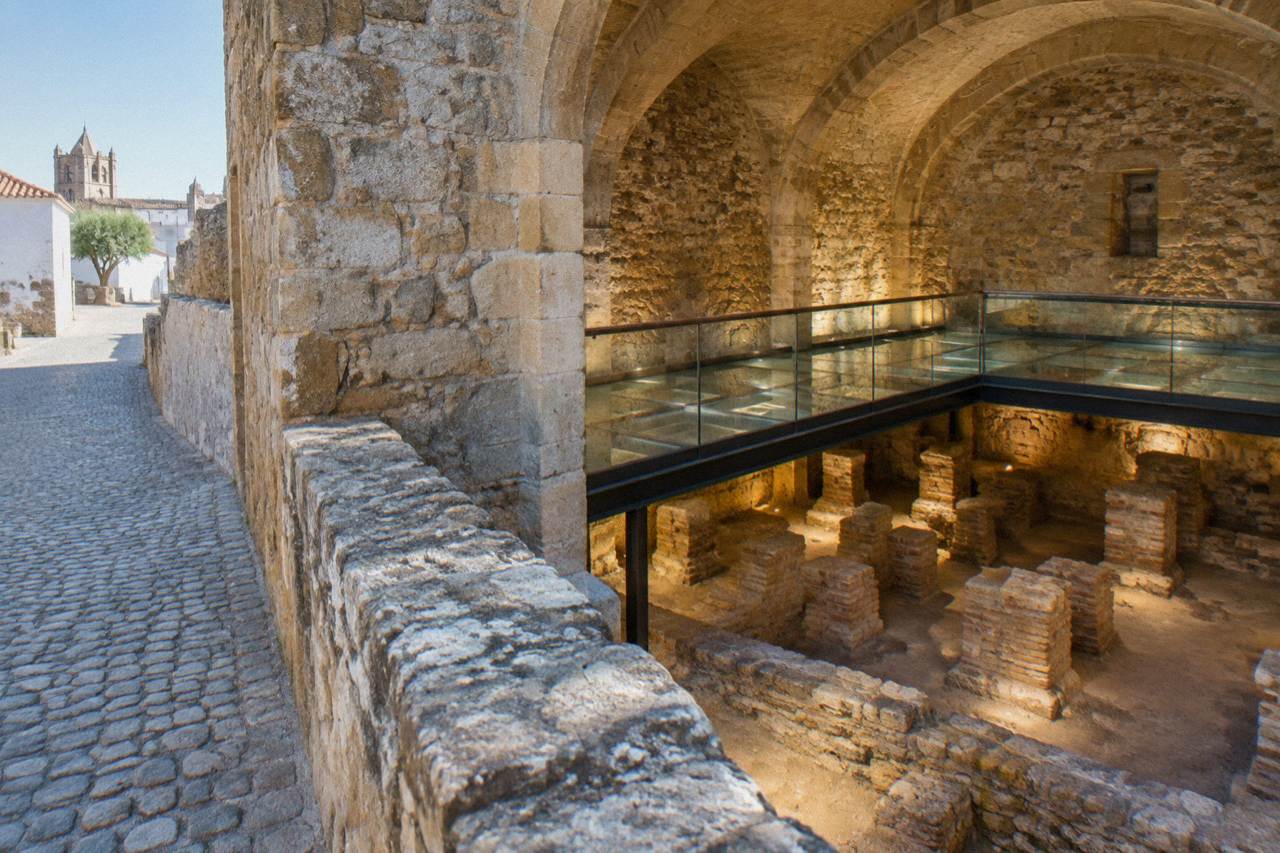 Exposed ancient stone walls of the Roman baths beside a cobbled street inside the walled centre of Évora