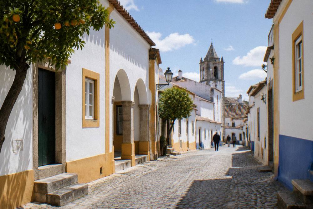 A train arriving at the small station of Évora under a wide Alentejo sky