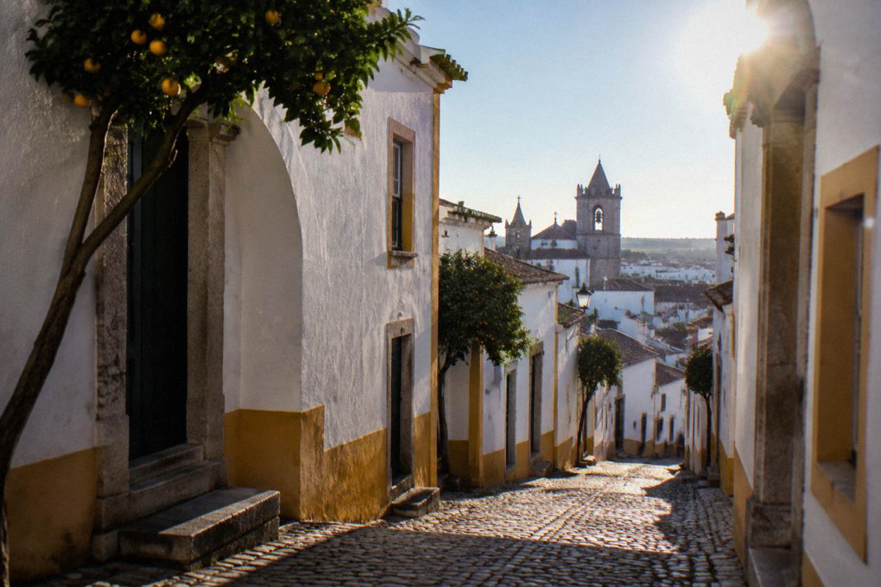 Rooftops of Évora with white houses, terracotta tiles and church towers under a clear sky