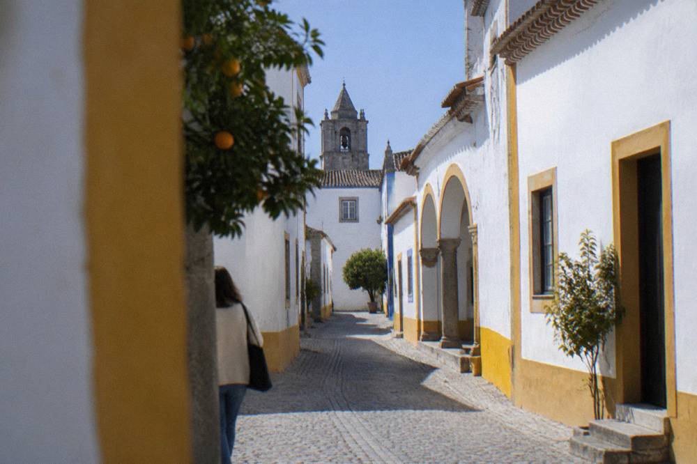 White houses and a church tower of Évora seen from a narrow street near the Roman temple