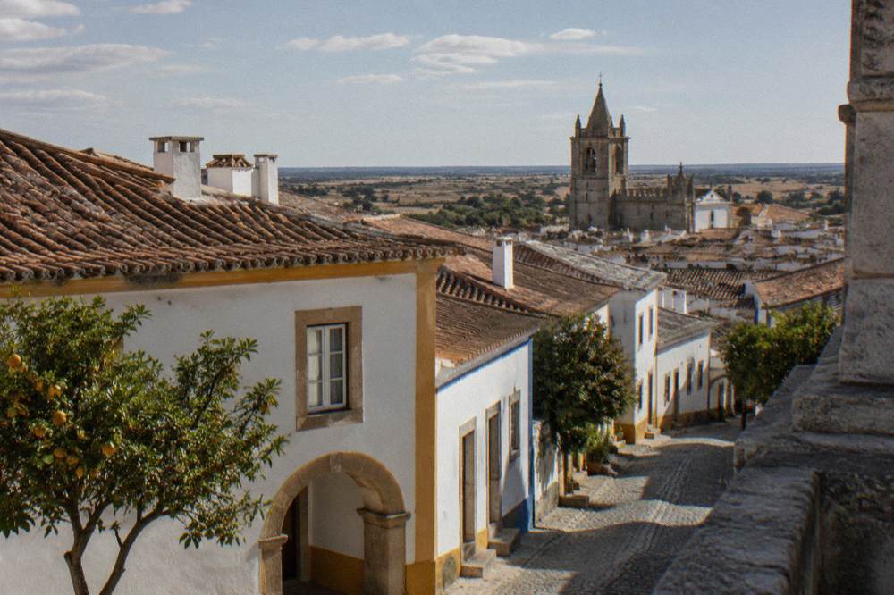 Terracotta rooftops and a bell tower of Évora seen from a church terrace in late afternoon light
