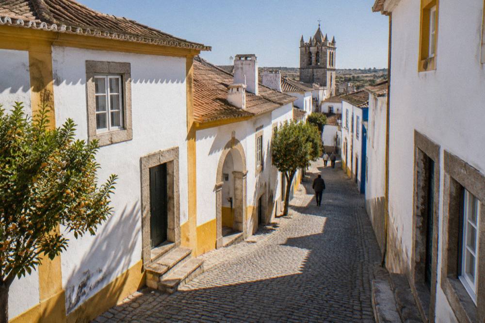White houses with granite doorframes on a narrow street inside the walled centre of Évora