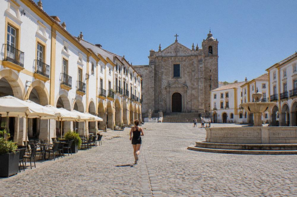 Morning light on the arcaded facades and stone paving of a historic Alentejo town square