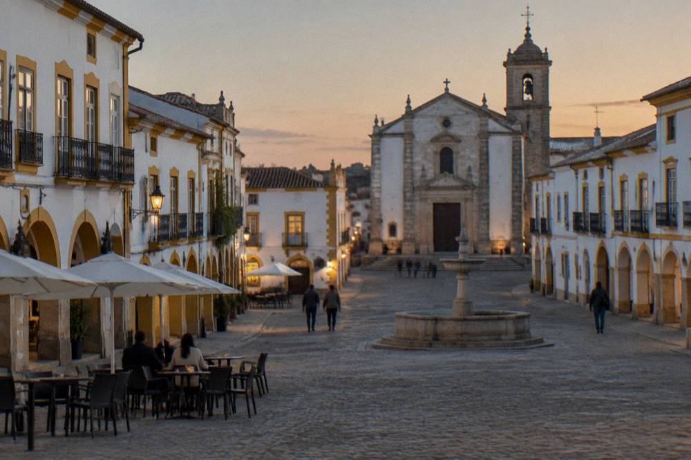 Evening light over rooftops and a church tower in an inland Alentejo city