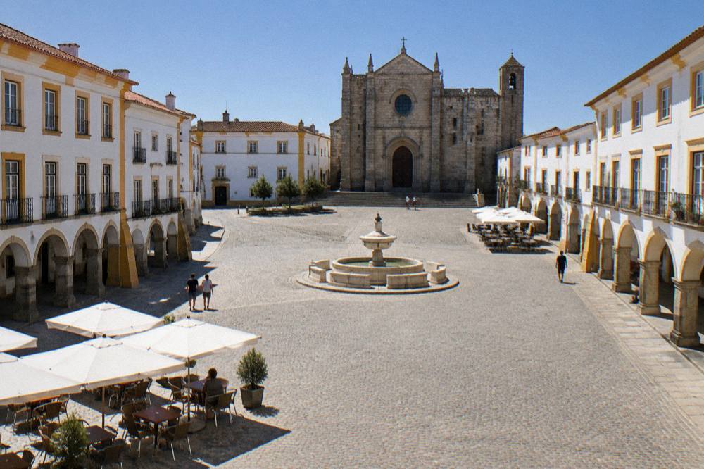 A quiet morning in a wide Alentejo square with white buildings and a clear sky