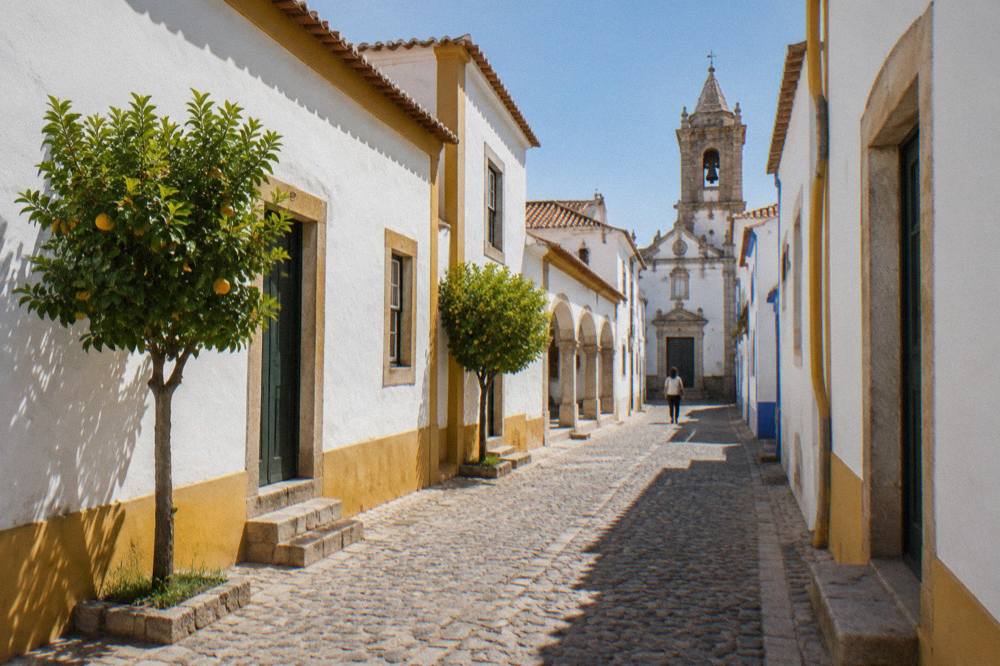 Whitewashed lane in Évora leading toward a church facade with a bell tower