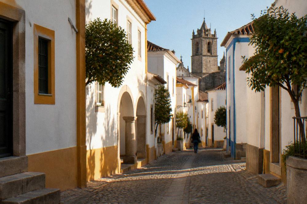 Golden late afternoon light on whitewashed houses and a church tower in Évora