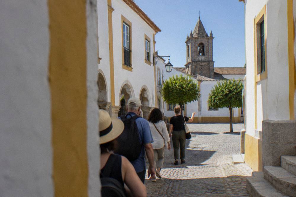 Small group of visitors following a guide through a sunlit square in Évora