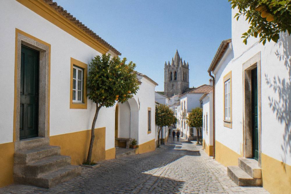 Sunlight falling on whitewashed walls and stone paving in a narrow old street in Évora