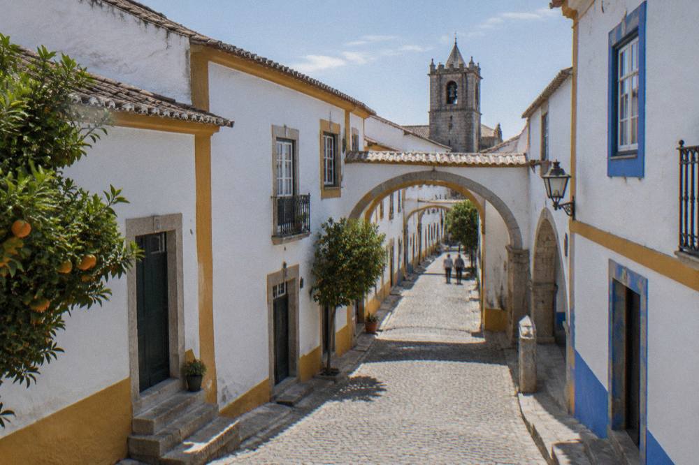 A quiet stone street with medieval arches and whitewashed houses in Évora