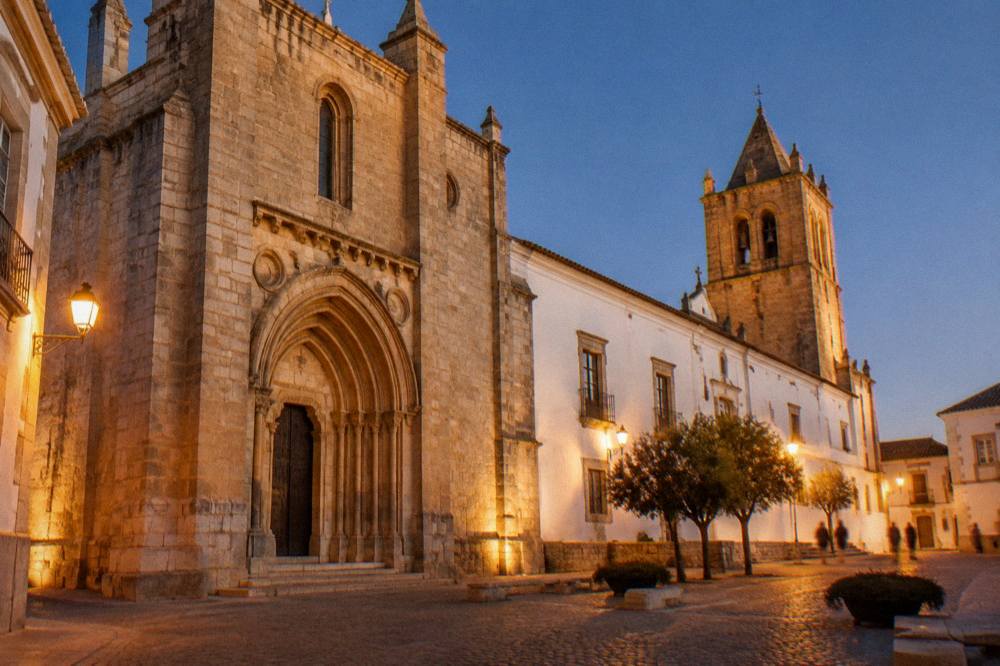 Golden evening light on stone buildings and a church tower in Évora's old centre