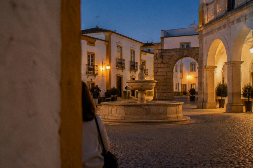 Golden evening light on whitewashed houses and a stone fountain in a small Alentejo square