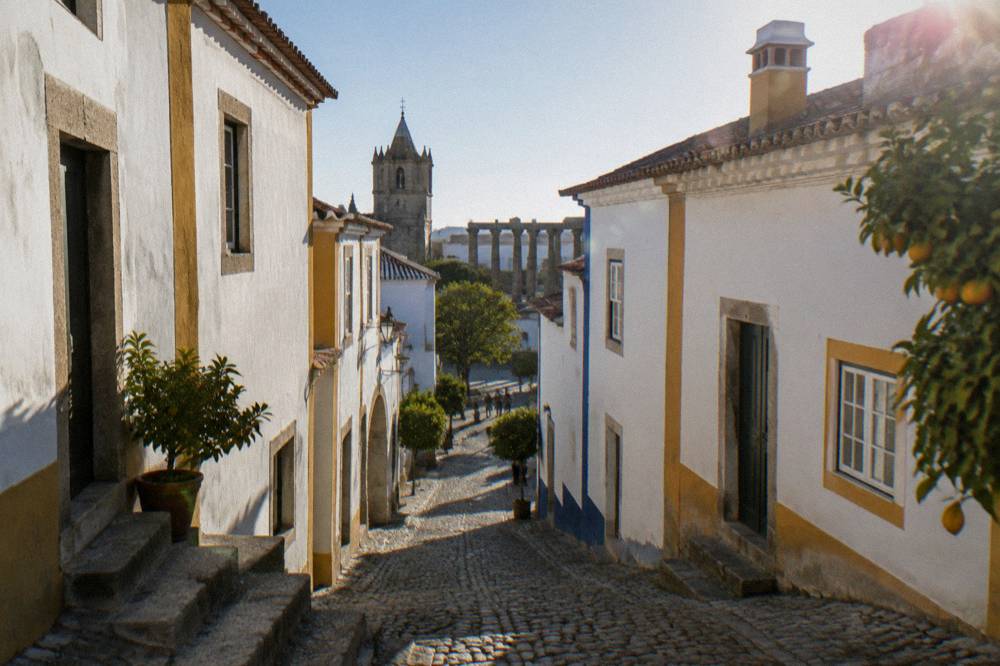 Narrow cobbled street in Évora's historic centre leading toward the temple square