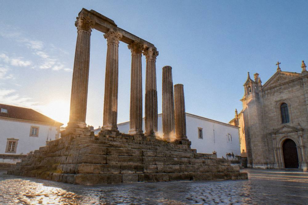 Sunrise light striking the temple columns with an empty square below