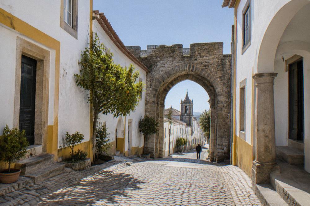 An old stone gate in the walls of Évora with a narrow street passing through it