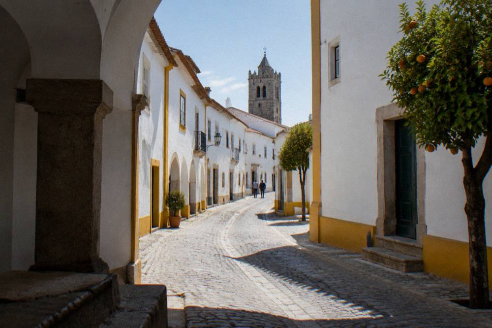 A quiet cobbled street in Évora curving along the line of the old wall