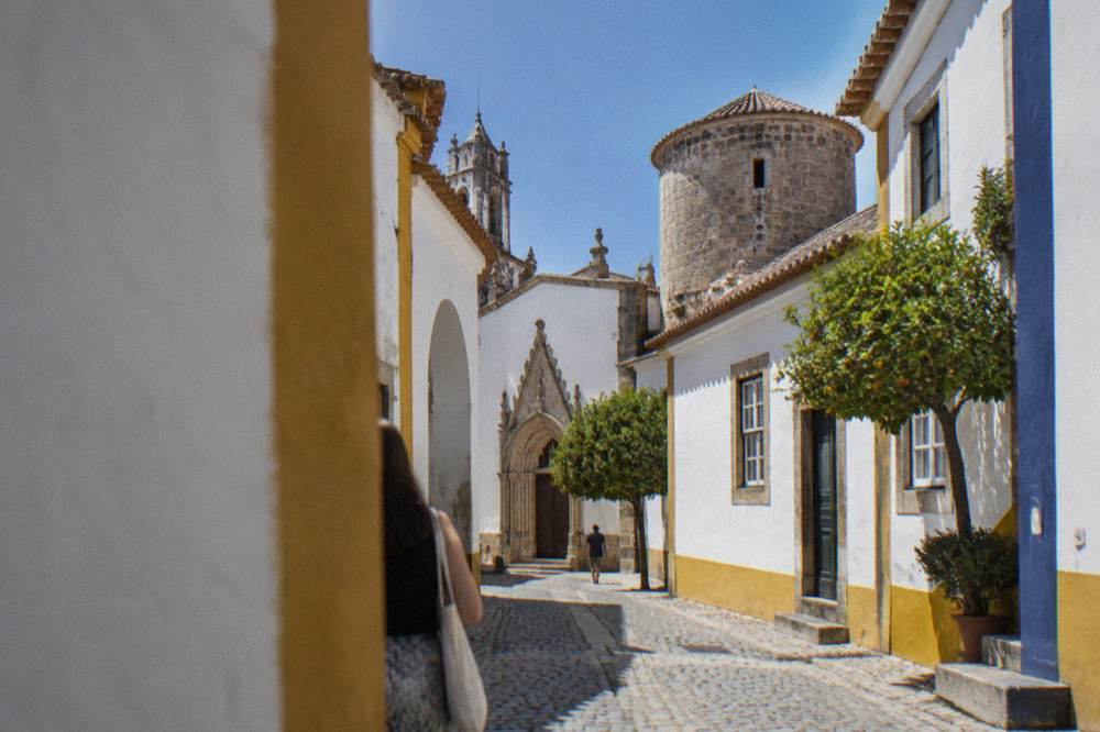 The carved stone doorway and round tower of a small chapel in Évora seen from street level