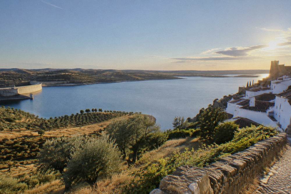 White-walled hilltop village of Monsaraz overlooking the wide Alqueva lake at sunset